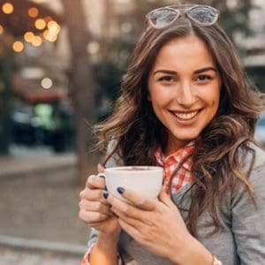 Poidmore Orthodontics - Woman smiling drinking coffee outdoors